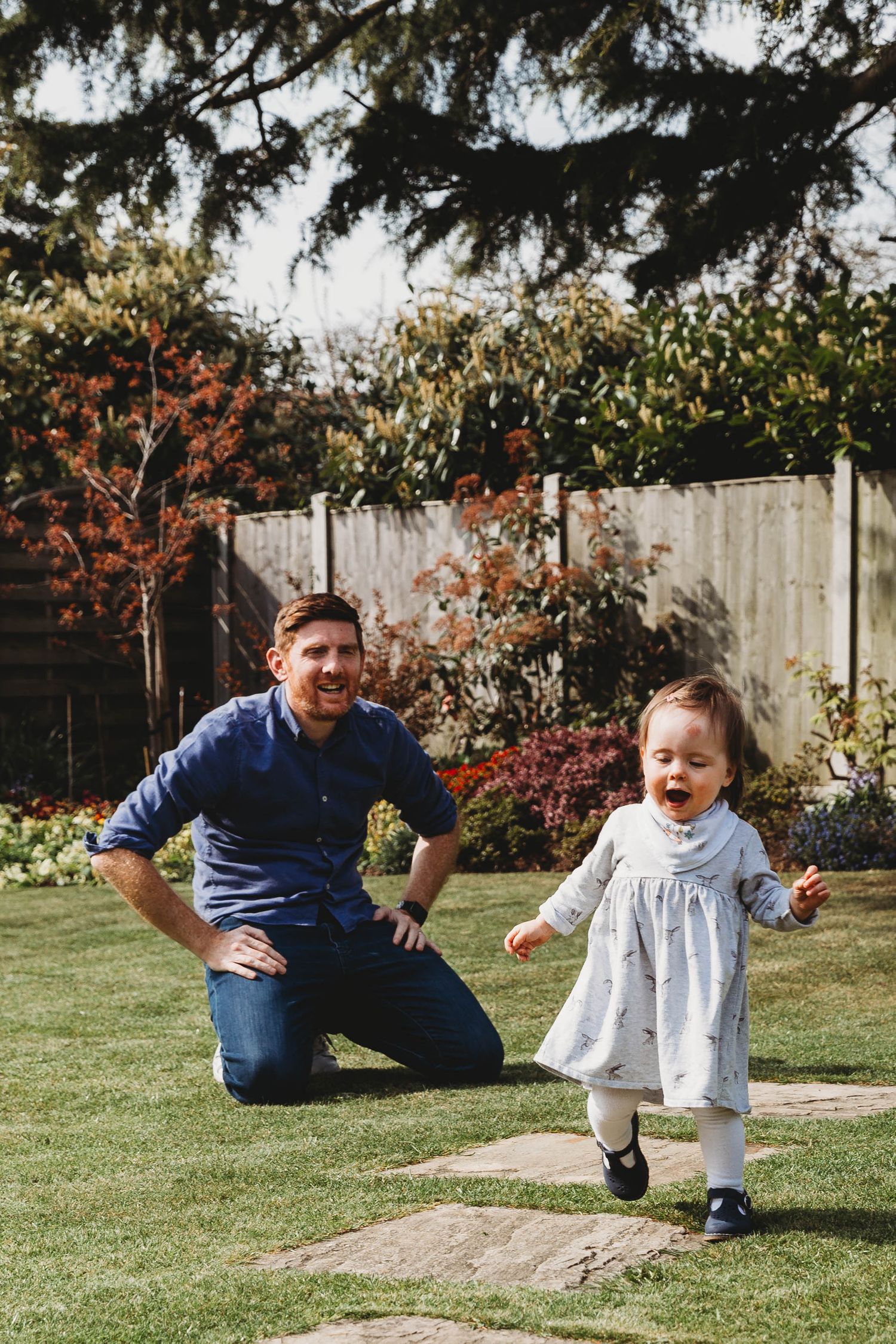 dad playing with toddler girl in garden