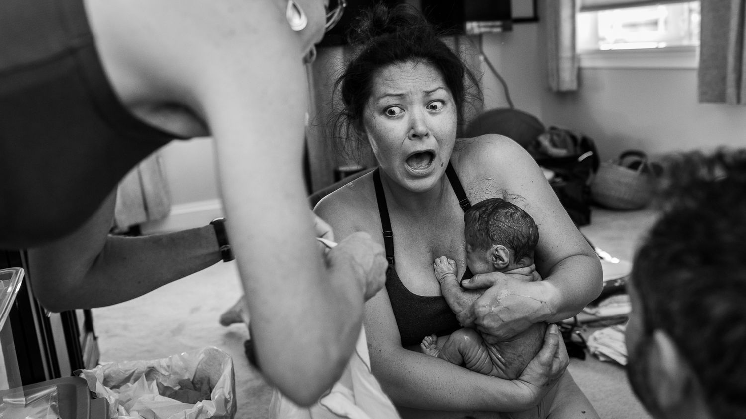 Mother looks astonished as she pulls her baby to her chest during her Longmont, CO home birth