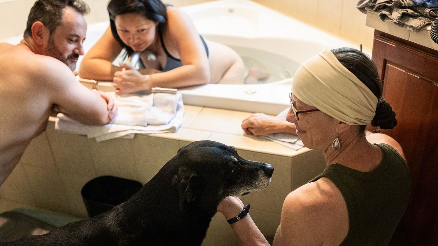 A midwife shares a moment with the family dog during labor at a Longmont, Colorado home birth