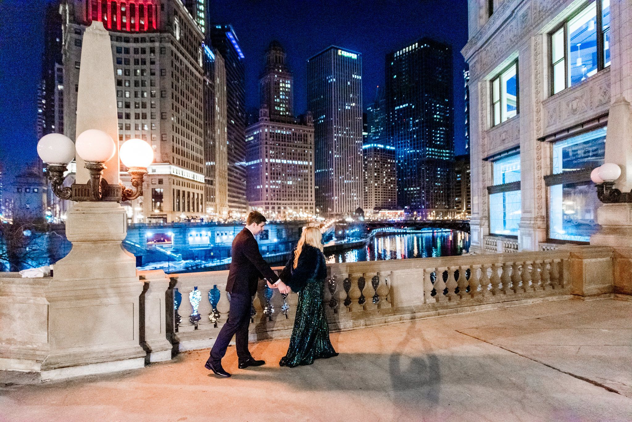 woman in sparkly green dress walking with man near the Wrigley Building for Chicago engagement pictures
