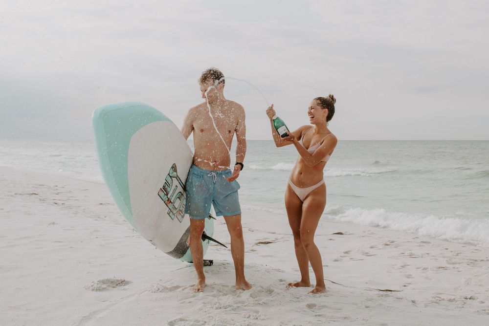 Couple popping champagne on the beach