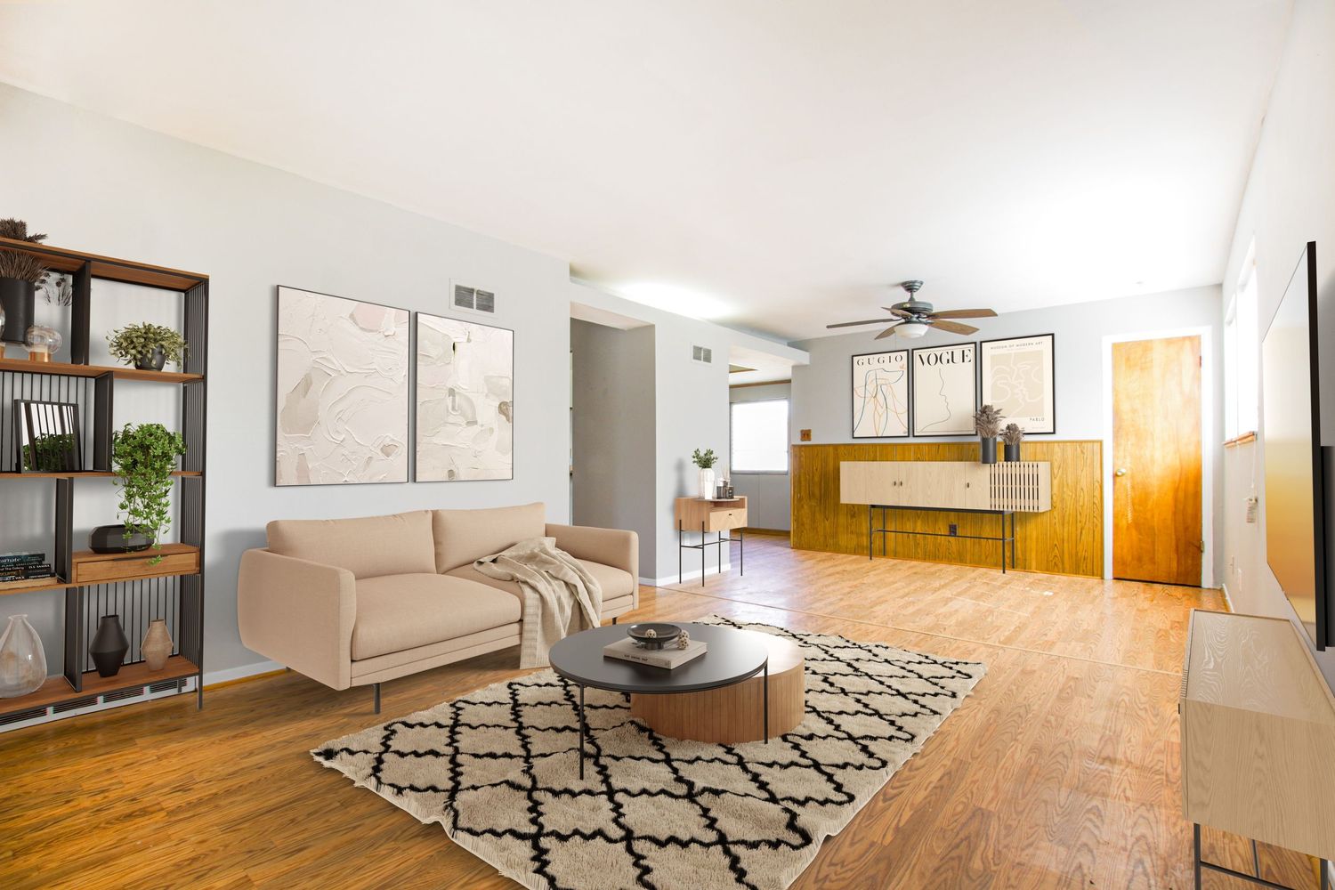 Contemporary living room with tan sofa, geometric rug, and open floor plan layout.