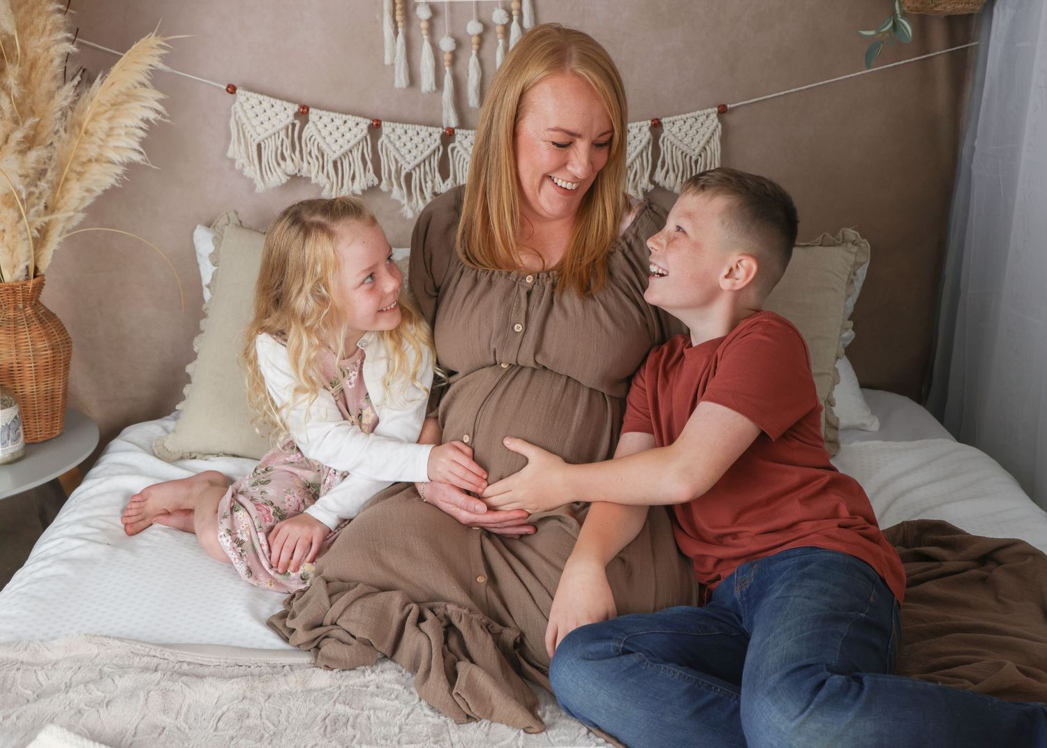 Pregnant woman with her two children holding the bump