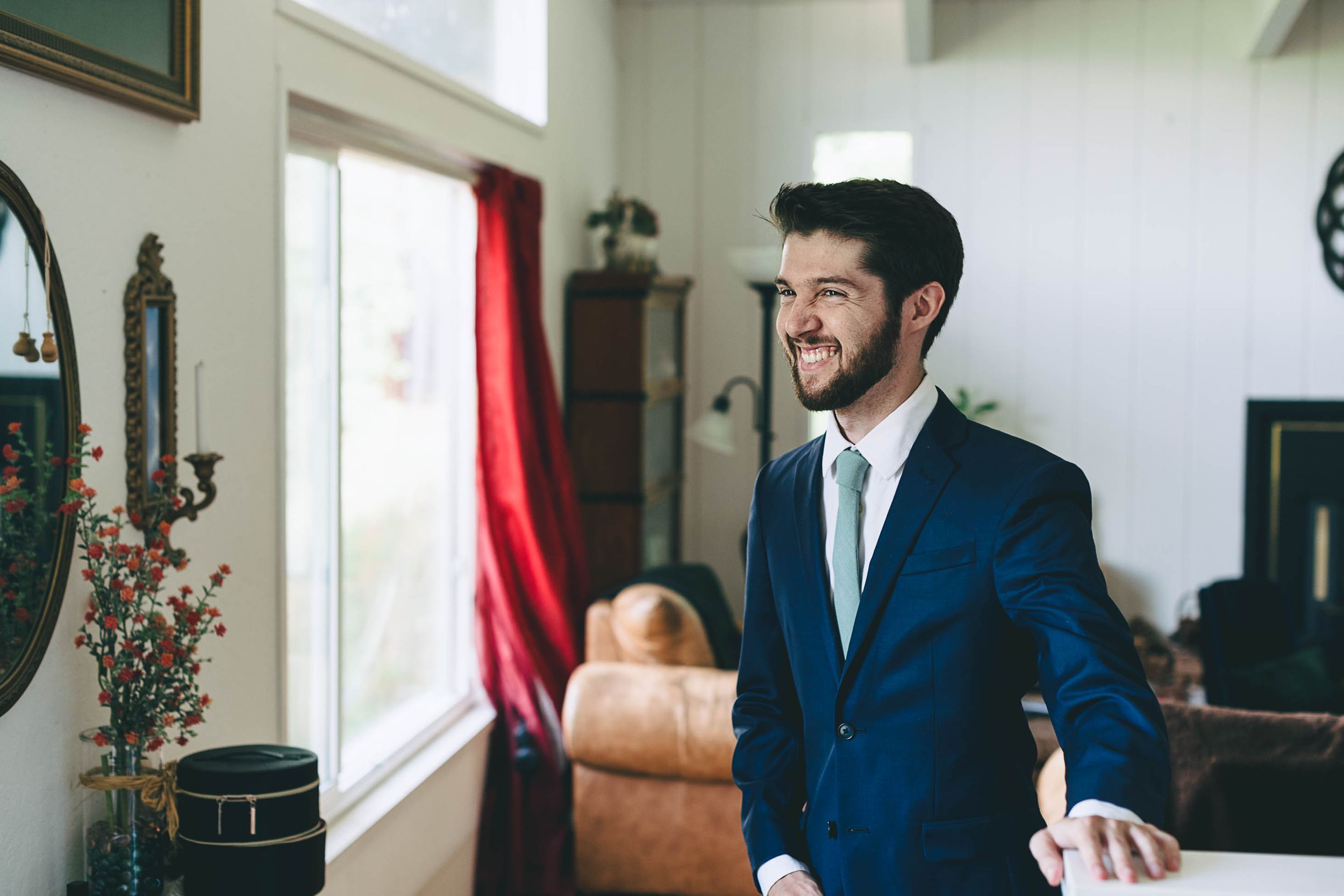 Groom smiling in his blue jacket and forest green tie.