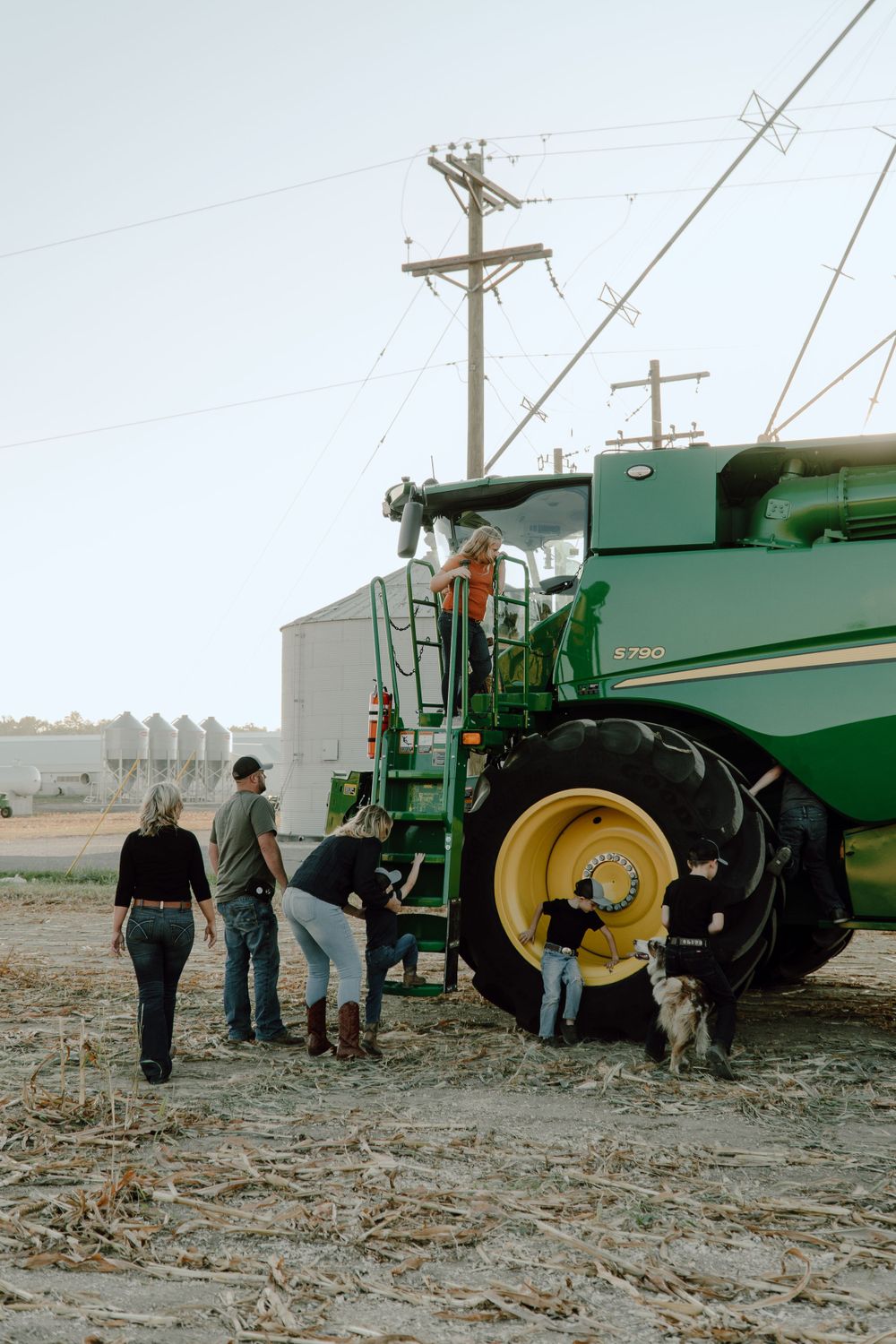Farm workers gathered around a large green combine harvester in a field.