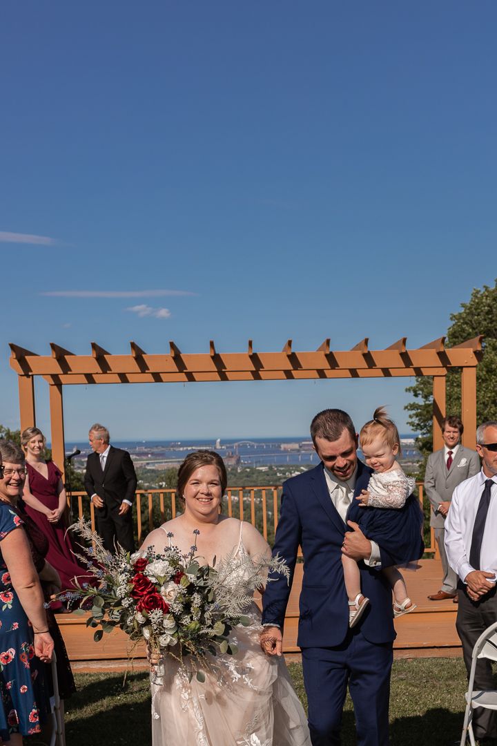 Duluth Minnesota Wedding Scene. Bride and Groom and their little girl walking down the aisle after saying I Do.