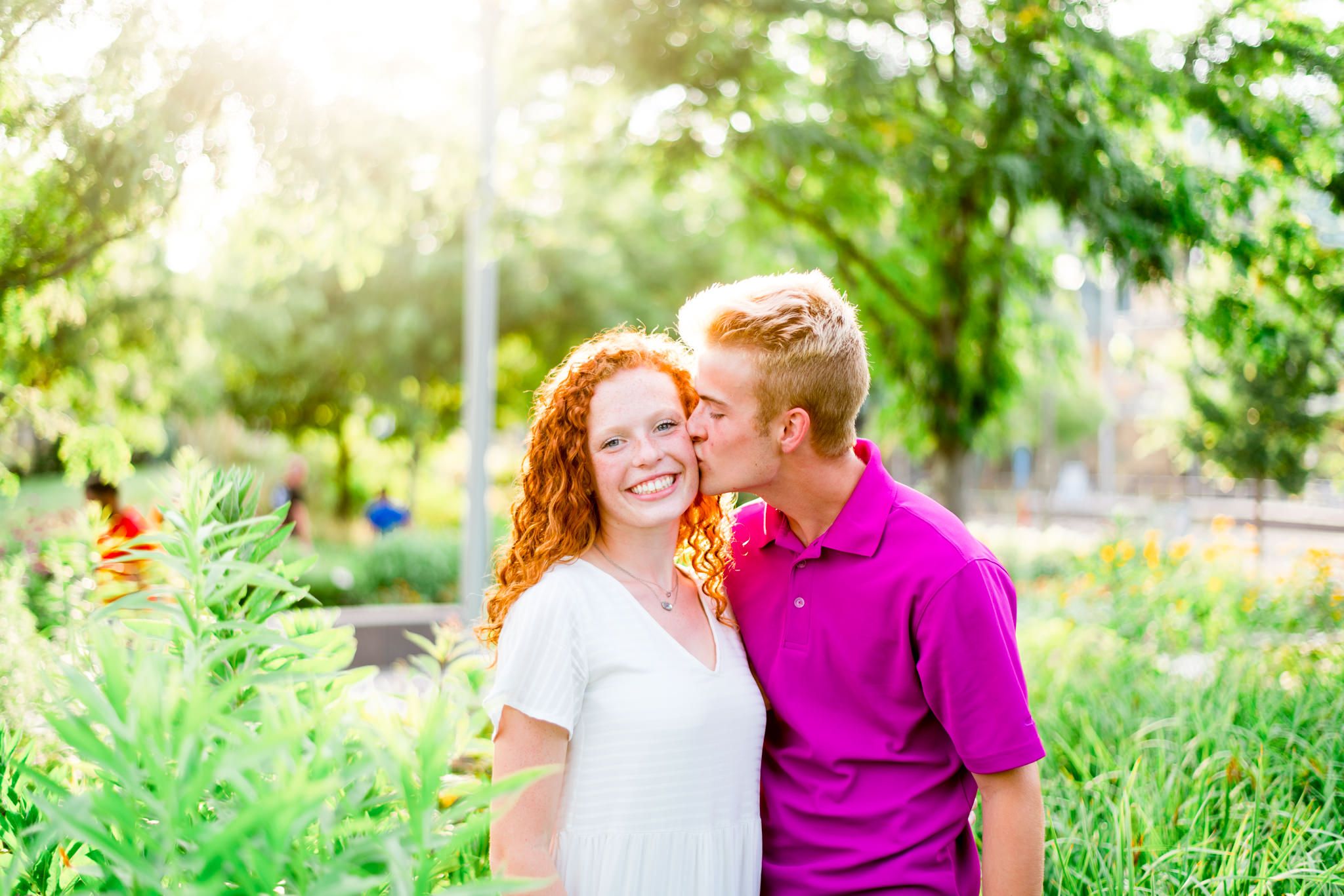 young man kissing young woman with red curly hair on the cheek in the flowers at Smale Park Cincinnati
