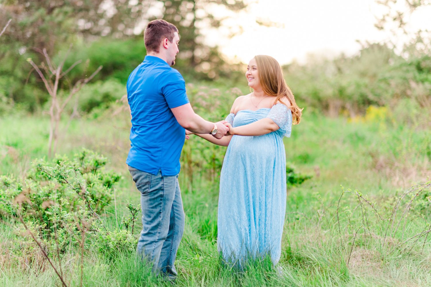 Maternity session with couple dancing in field in golden hour sunlight at Moraine State Park, Pennsylvania