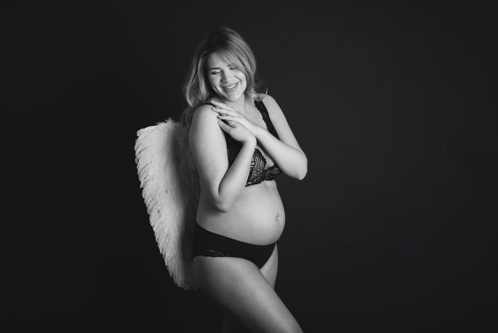 pregnant woman smiling in underwear with white wings