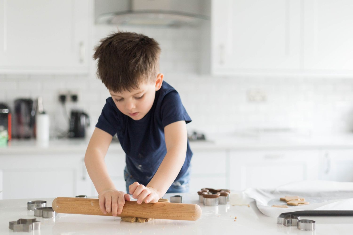 little boy rolling cookie dough with rolling pin