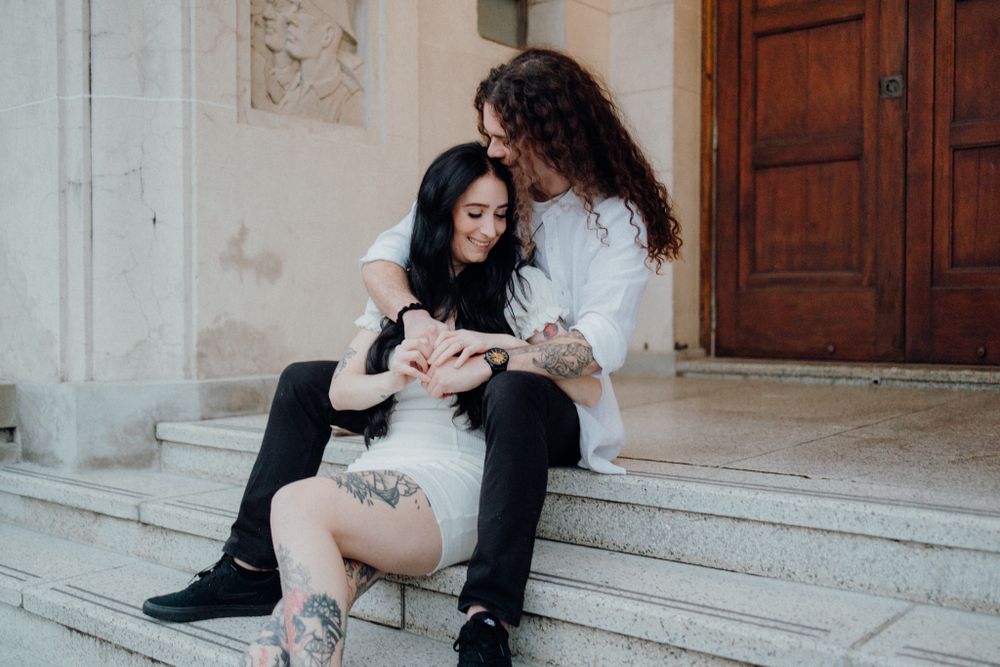 A couple sits together on stone steps examining something in their hands.