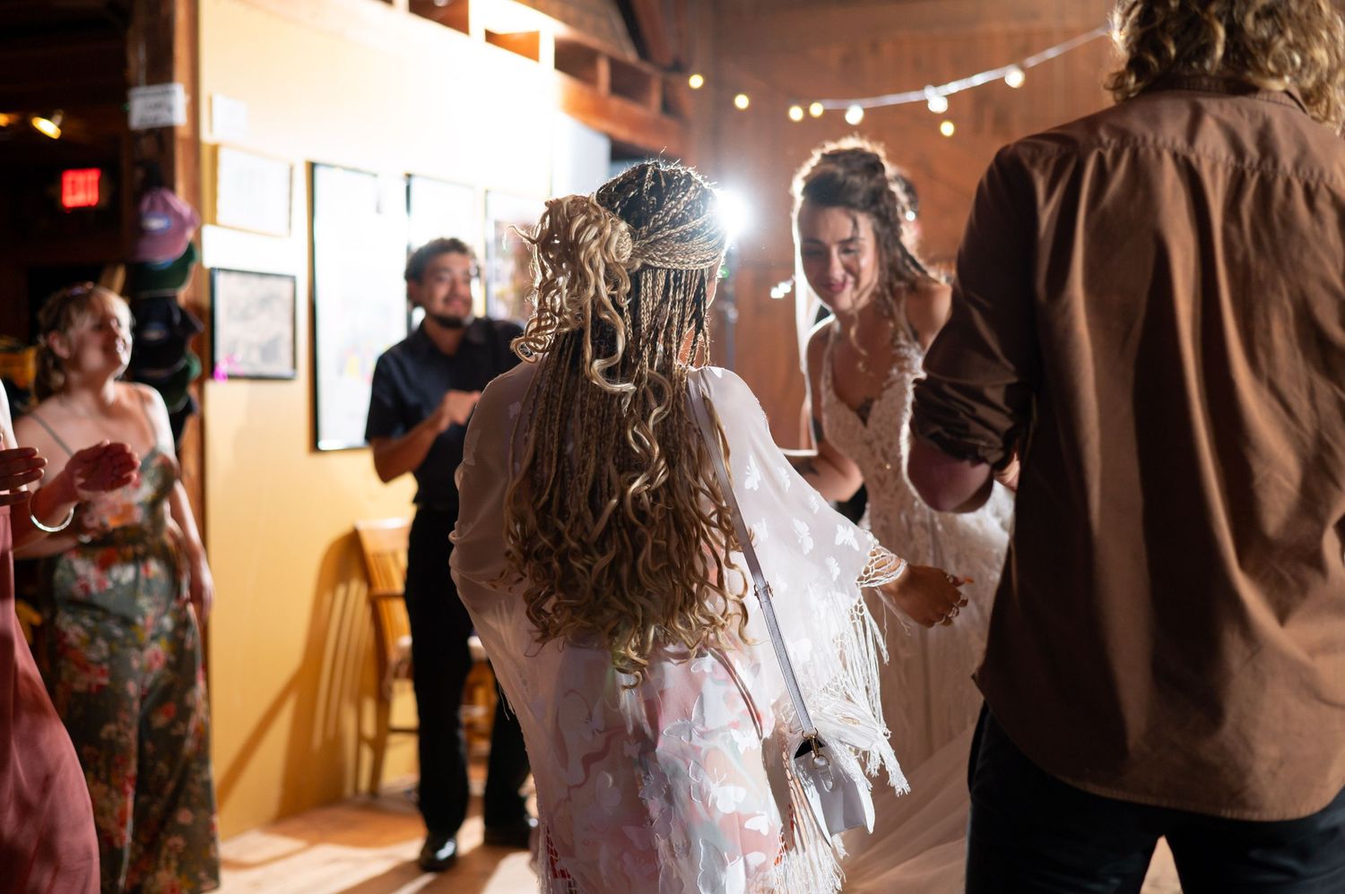 Wedding reception celebration with guests dancing and festive lighting.