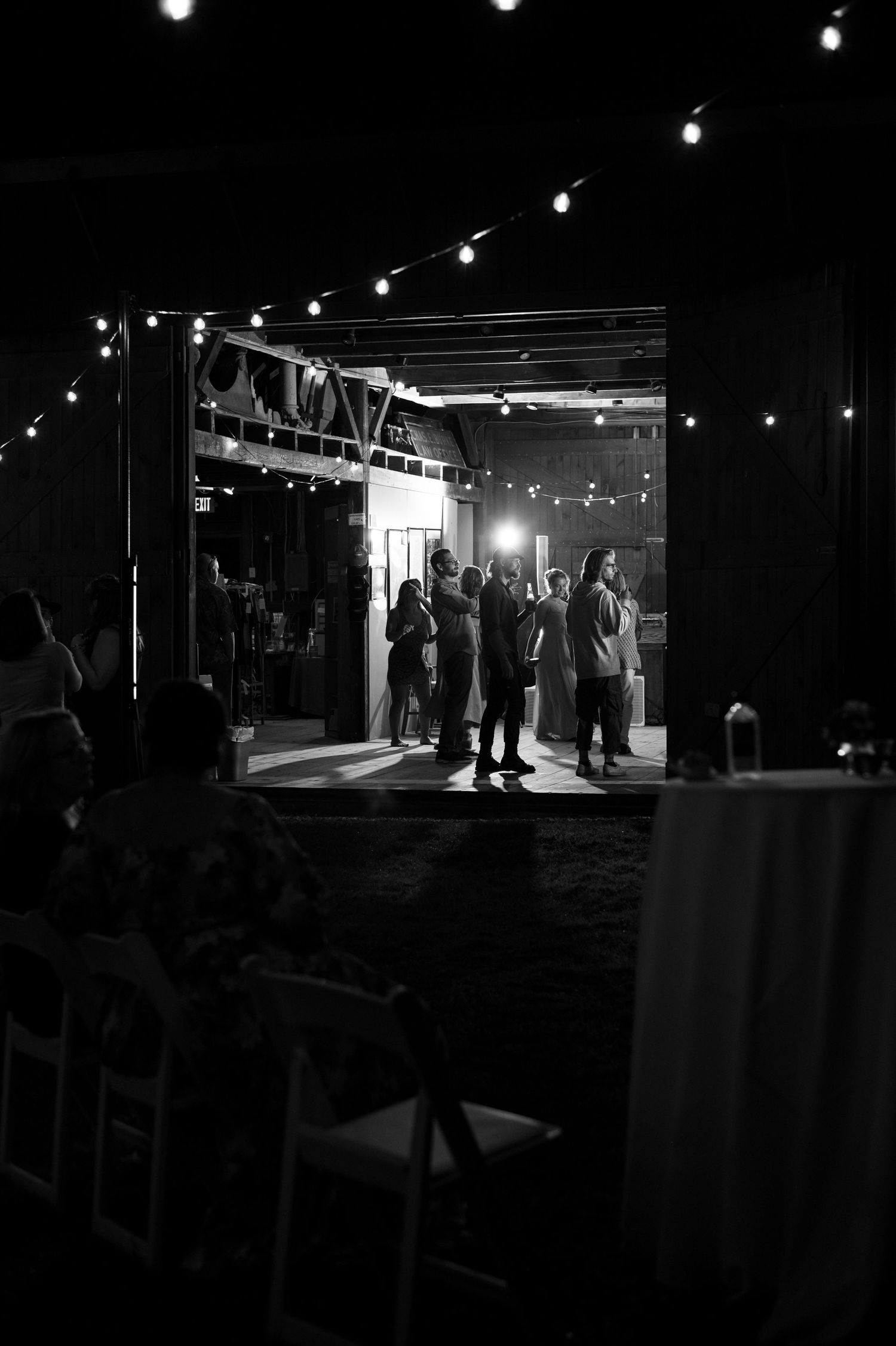 String lights illuminate a dark venue entrance as silhouettes of guests gather in the doorway.