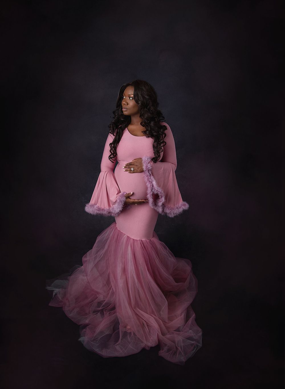 Beautiful maternity portrait of a pregnant woman wearing a couture maternity gown with bell sleeves and pink tulle skirt