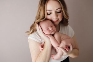 A mother holding her newborn baby in a photography studio in Perth