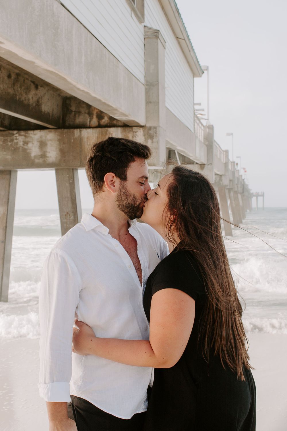 couple kissing in front of the Okaloosa Island Pier during their sunrise couples session