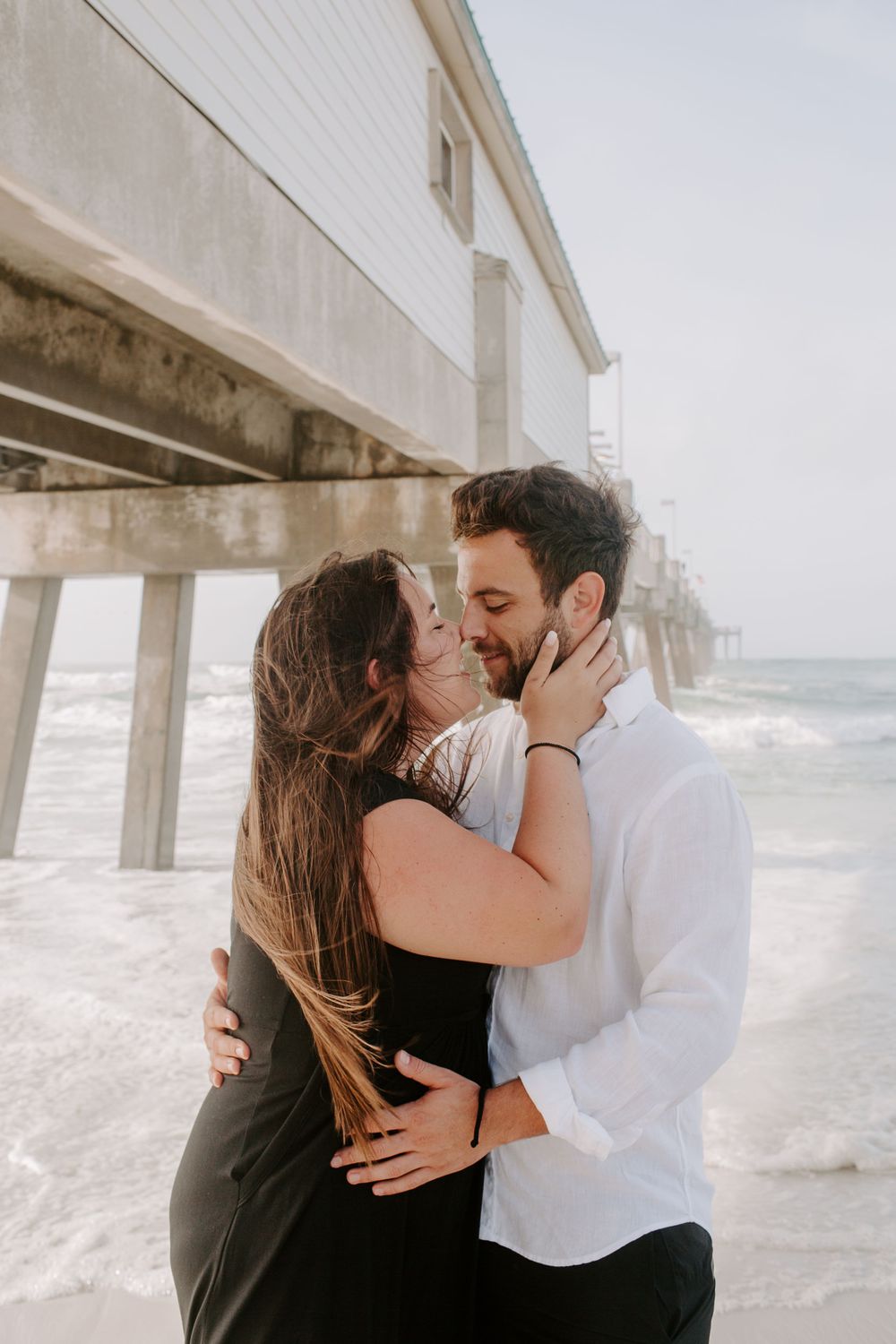 couple about to kiss in front of a pier during their Florida couples session