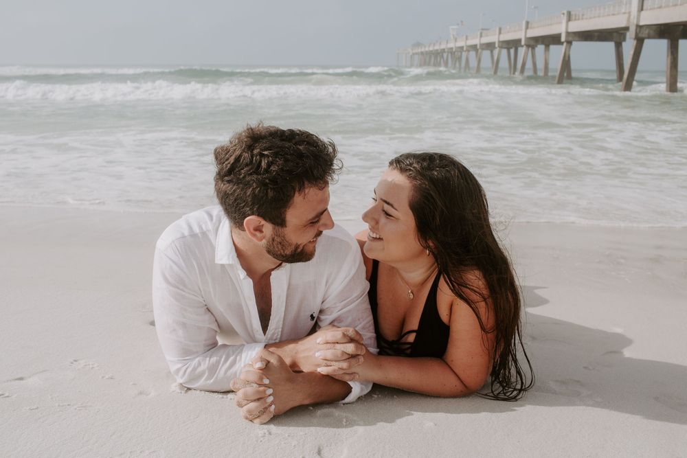 couple laying down on the beach in Destin, Florida looking at each other
