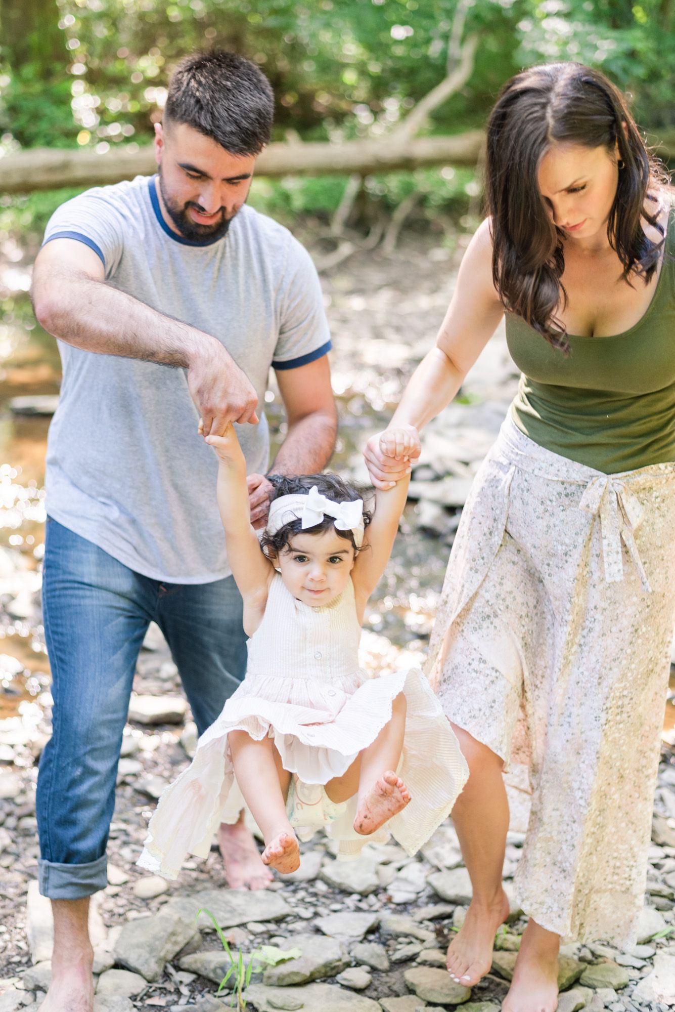 Family swinging toddler in creek in Pittsburgh, Pennsylvania