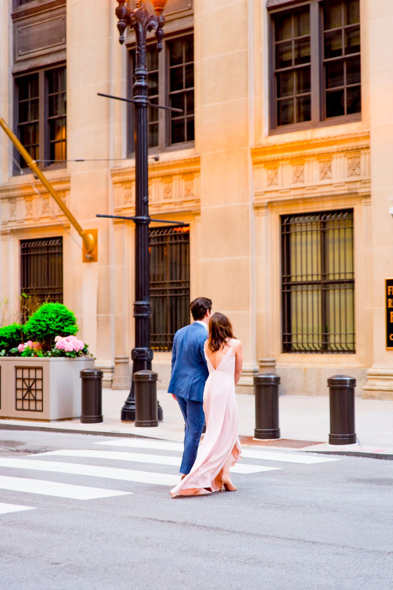 man and woman walk away towards Chicago Board of Trade for sunset engagement pictures in Chicago