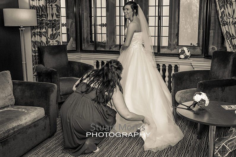 bridesmaid fastens the brides shoe under her wedding dress