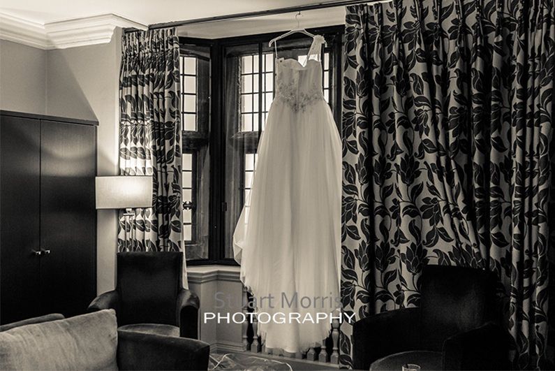 wedding dress hanging in hotel room window at abbey house barrow