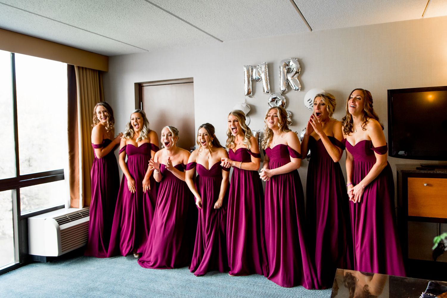 surprised bridesmaids in maroon dresses react to the brides final look