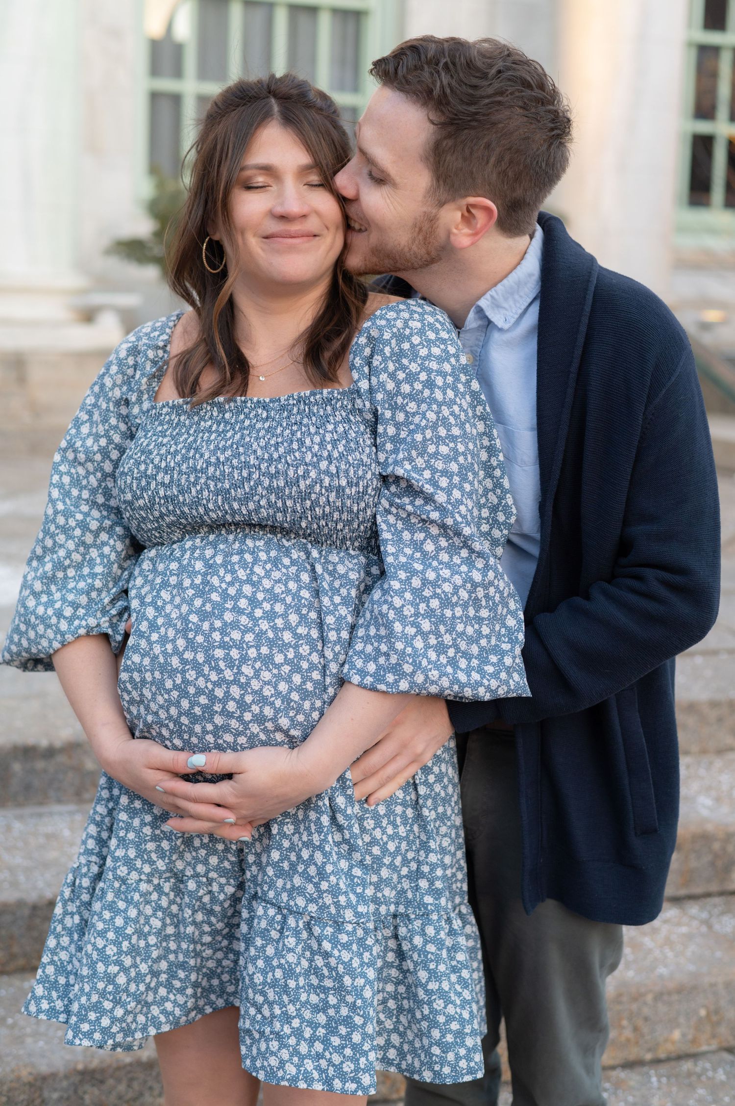 Intimate maternity portrait showing couple in blue dress and navy jacket.