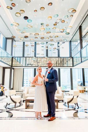 married couple in navy suit and silver dress holding champagne in lobby of The Langham Chicago