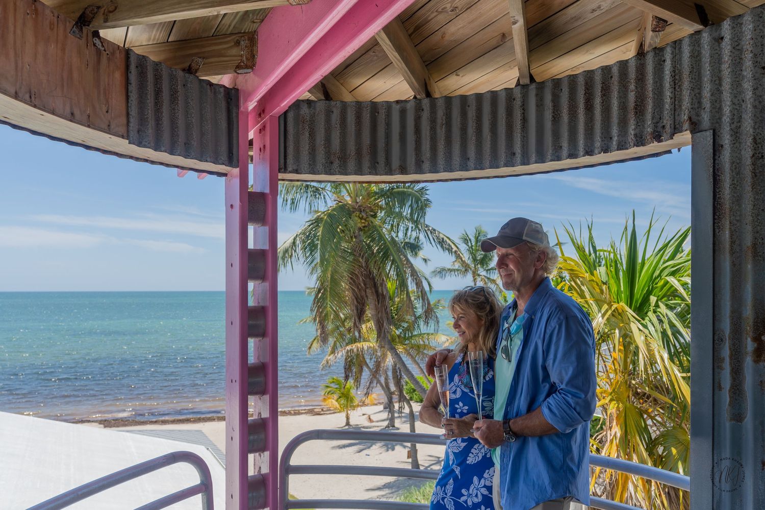 Couple enjoying ocean view from covered beachfront gazebo.