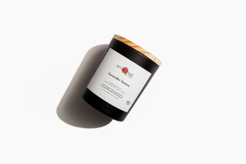 Minimalist black candle jar with white label photographed from above on white background.