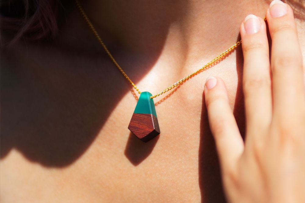 Delicate turquoise pendant on gold chain catching sunlight.