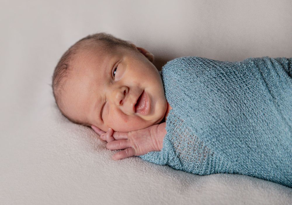 Newborn photography of awake baby swaddled
