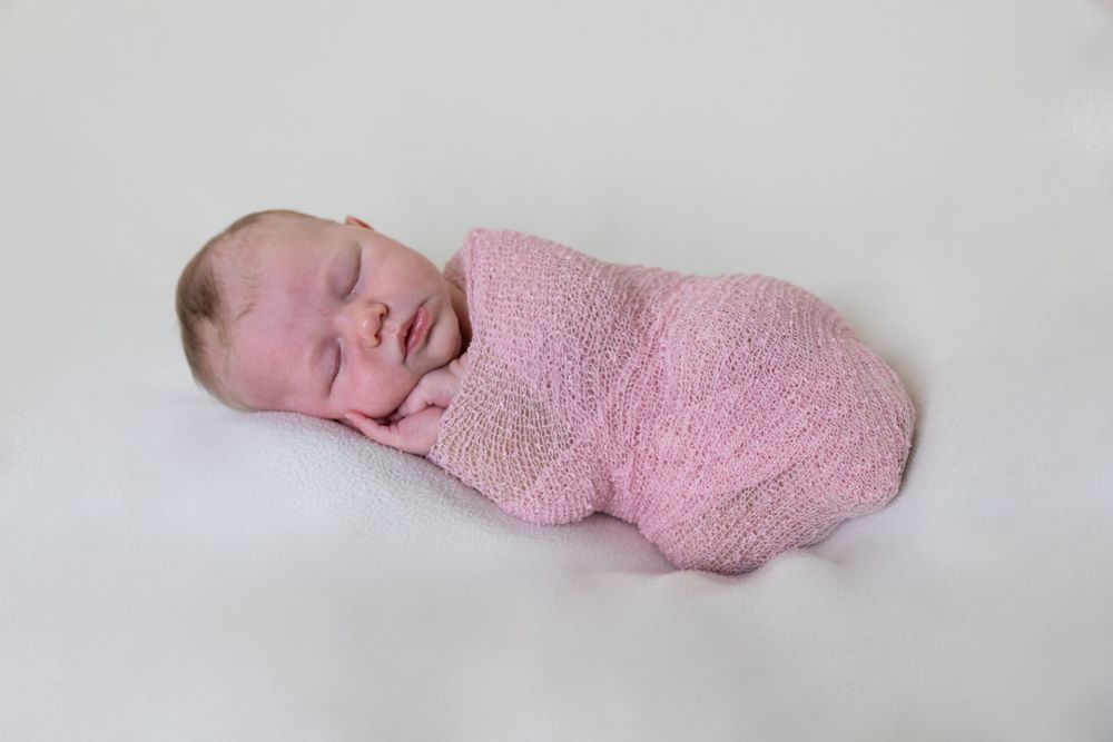Newborn photography of sleeping baby in pink swaddle