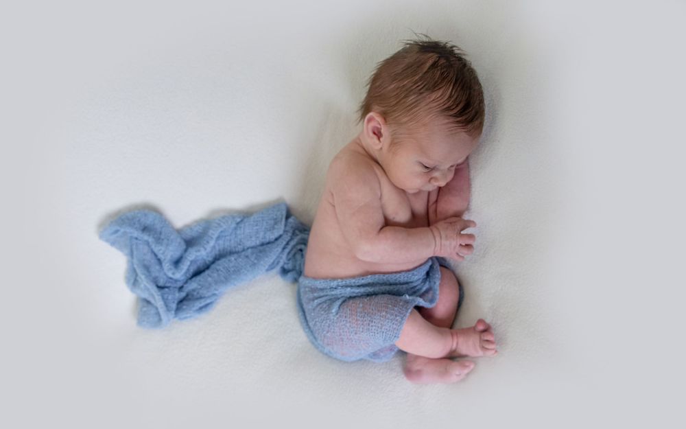 Newborn photography of sleeping baby in knit blanket