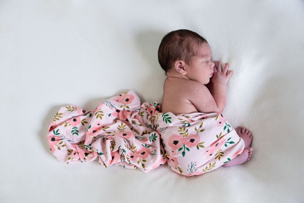 Newborn photography of sleeping baby in floral swaddle