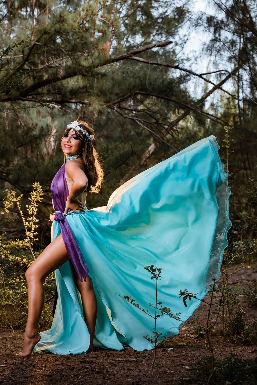 Flowing turquoise and purple dress captured in dramatic forest photoshoot.