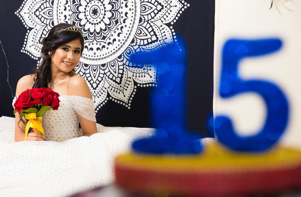 Celebratory quinceañera scene with white mandala backdrop and decorative number fifteen.