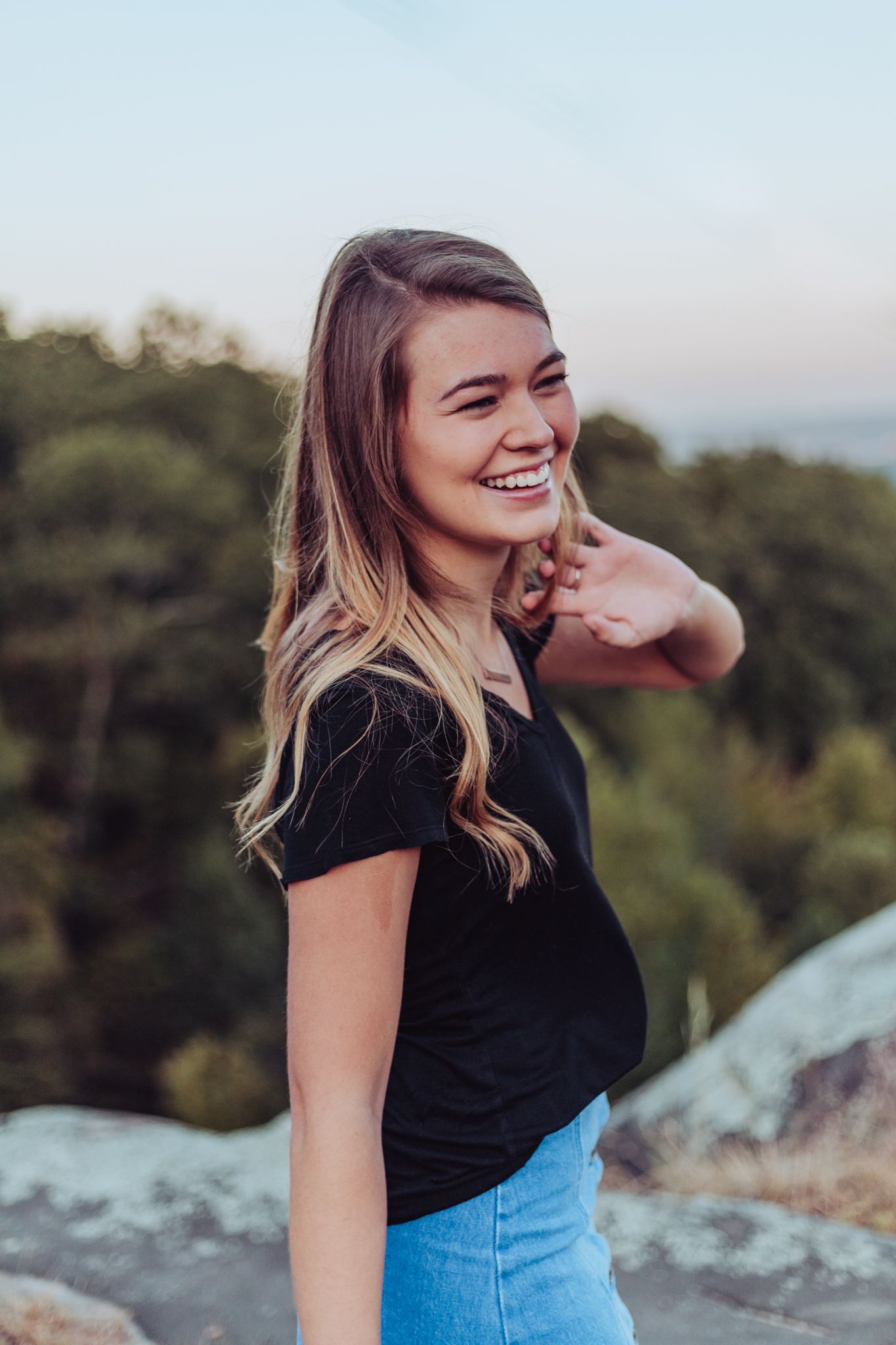 A young girl laughs while having portraits taken on a mountain