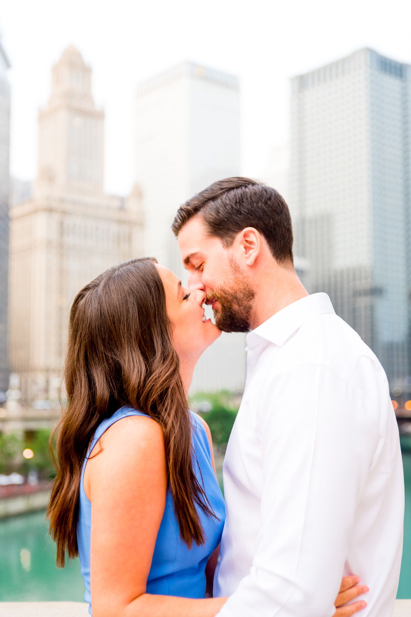 young engaged man and woman looking at each other in front of Chicago River near the Wrigley building at sunrise