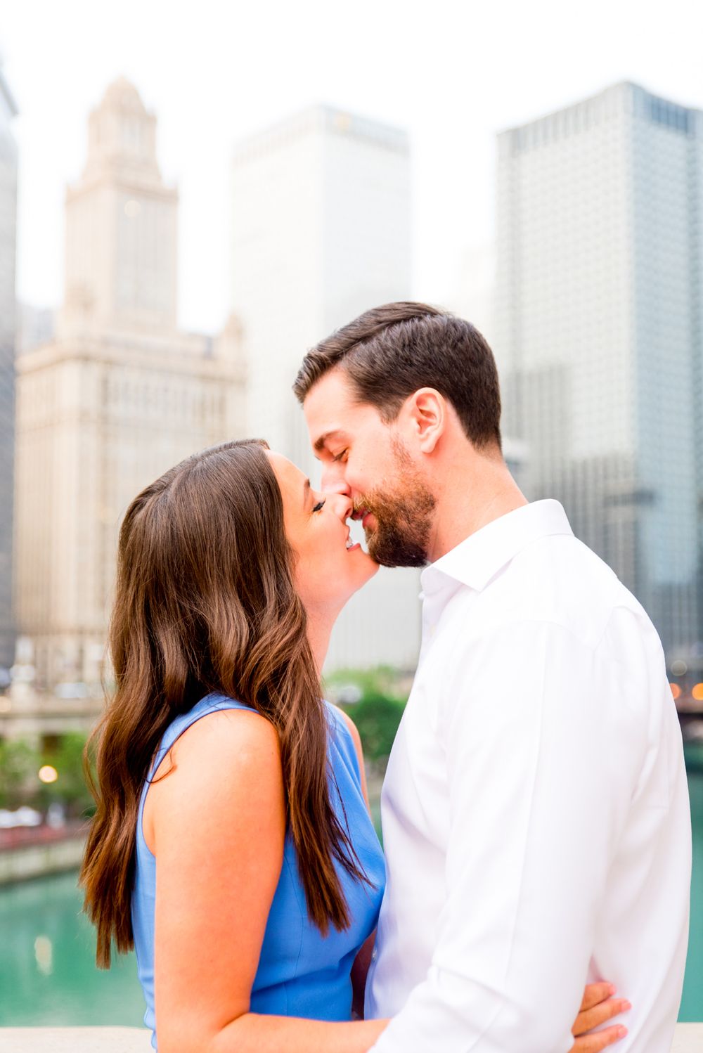 young engaged man and woman looking at each other in front of Chicago River near the Wrigley building at sunrise