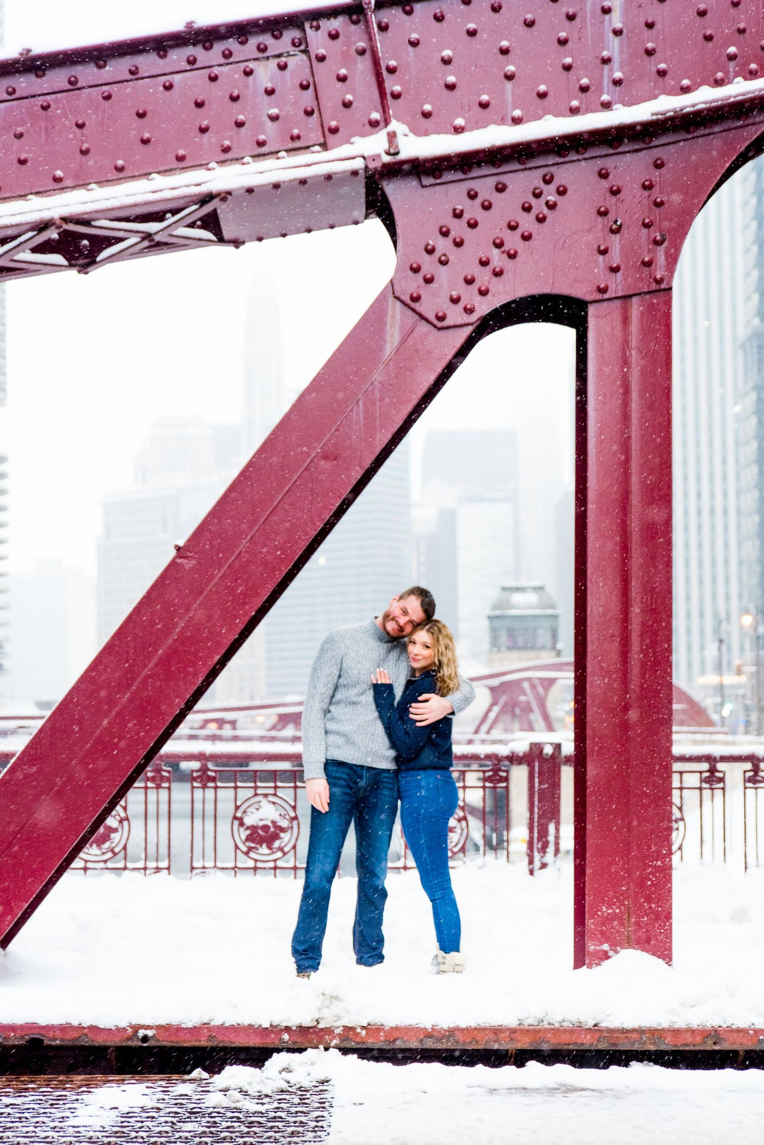 young couple hugging under bridge for Chicago urban engagement pictures in the snow