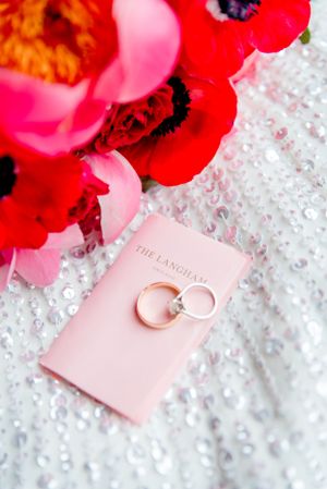 wedding bands on Langham key card with red flowers and sequin dress