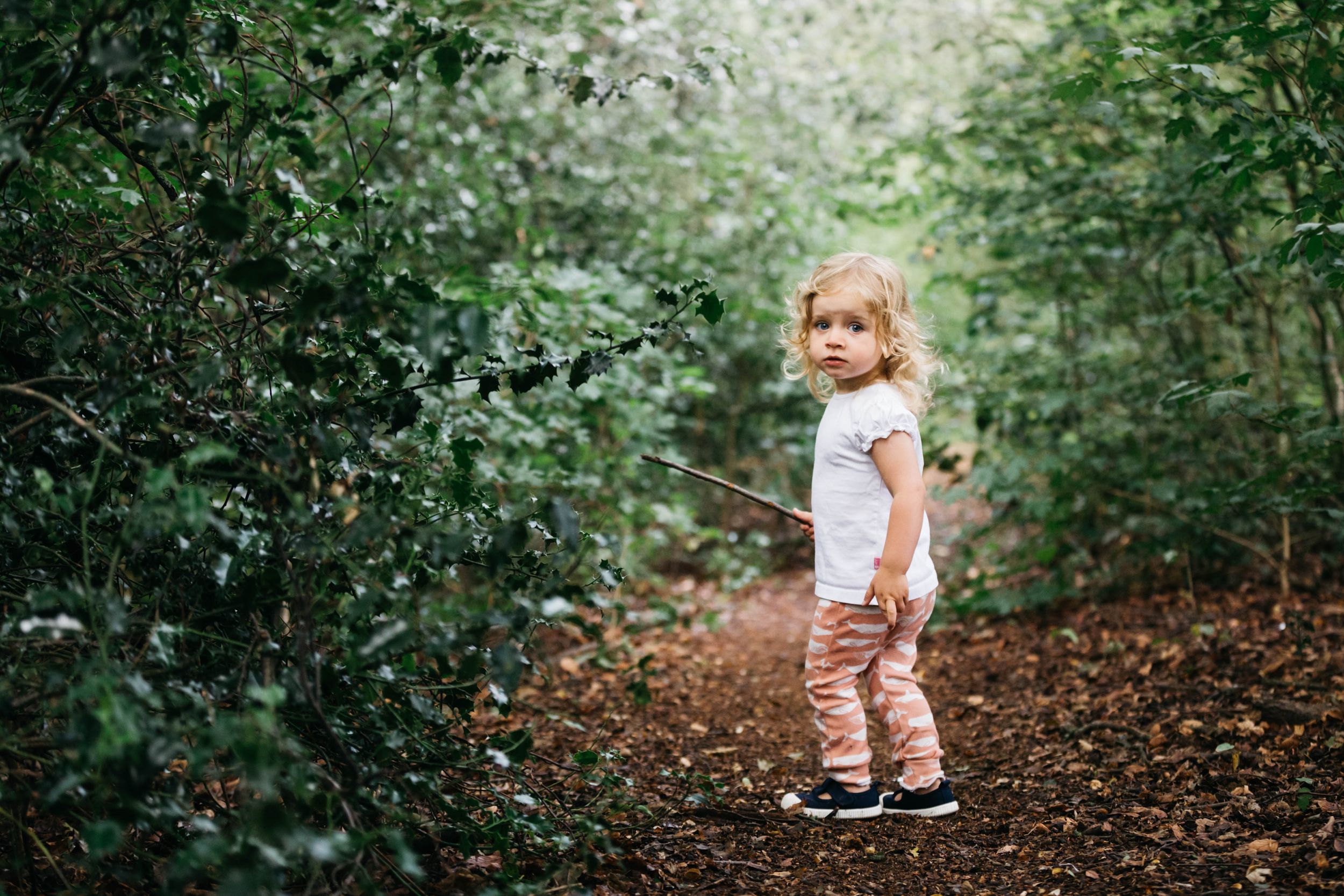 toddler girl with blonde curly hair turning towards camera