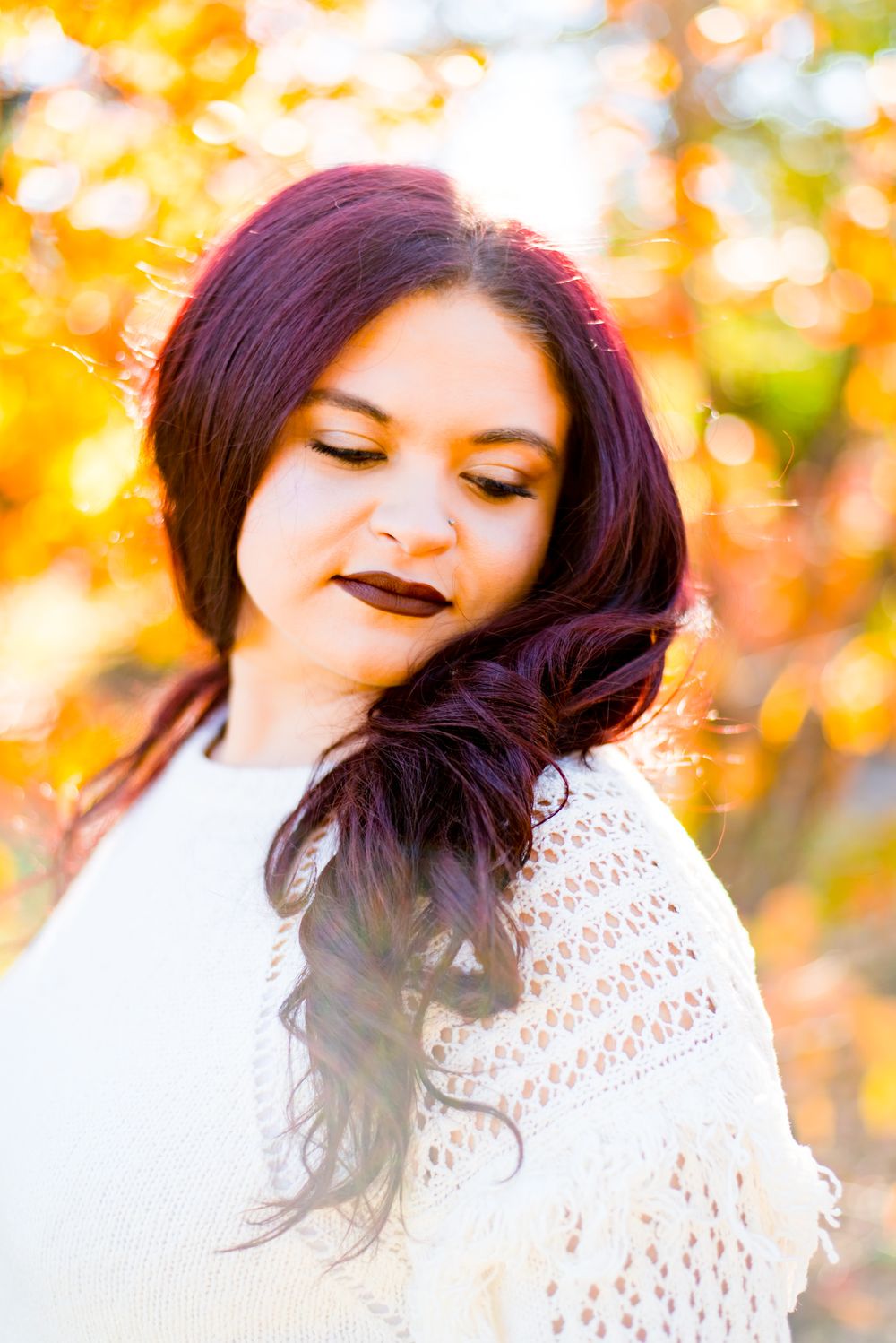 woman with red hair and lipstick looking at her shoulder, softly smiling in front of orange tree in Central Park