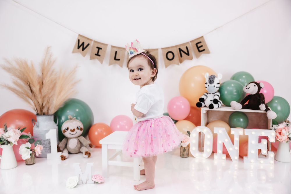 Wild One themed first birthday setup with pampas grass, stuffed animals and pink tutu.