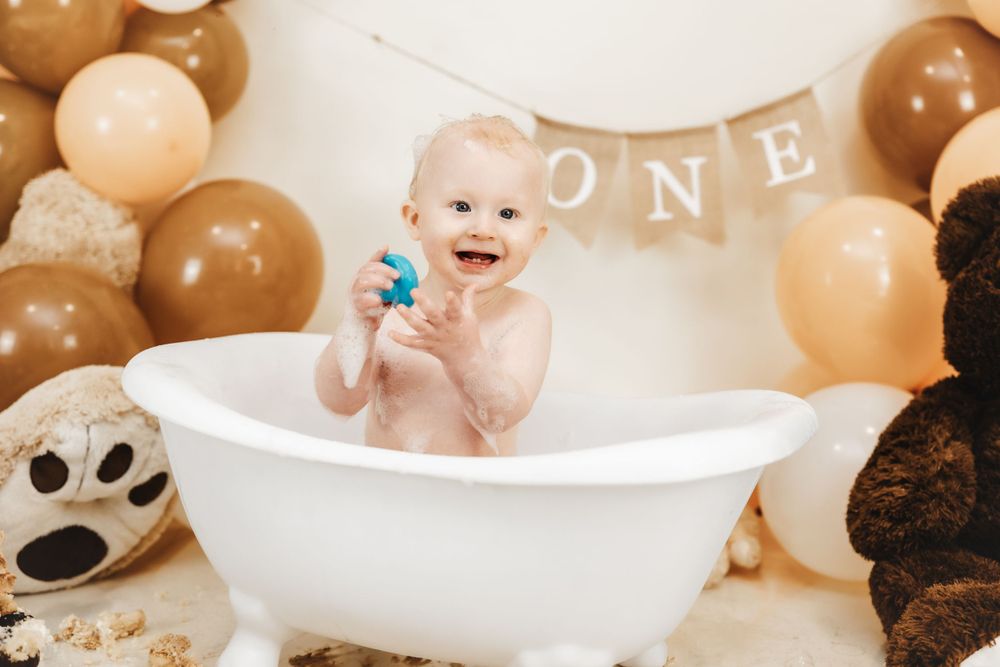 First birthday bath setup with brown and beige balloon decorations and teddy bear theme.