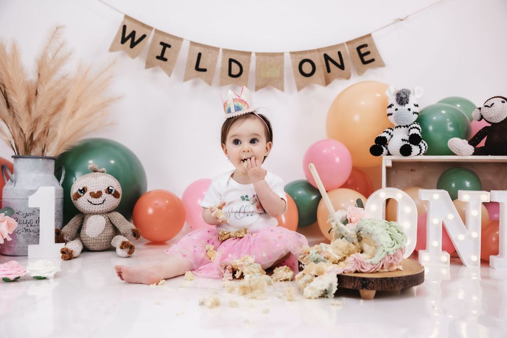First birthday photo with Wild One banner, pampas grass, and pink tutu outfit.