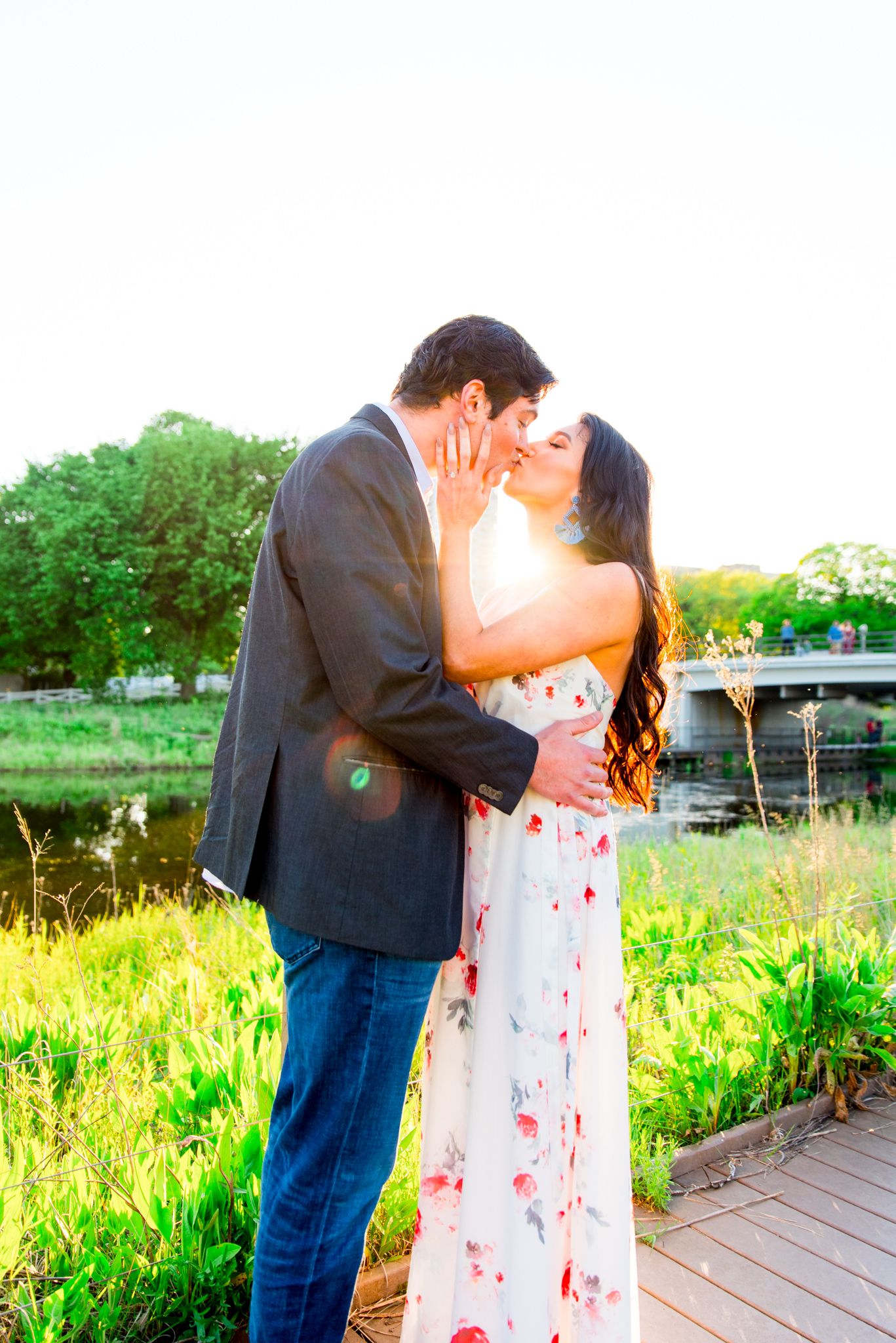 man in suit and woman in floral maxi dress kissing at sunset in Lincoln Park for engagement pictures