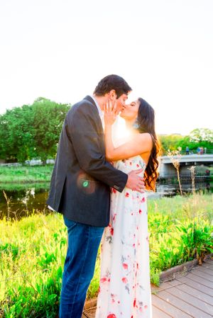 man in suit and woman in floral maxi dress kissing at sunset in Lincoln Park for engagement pictures